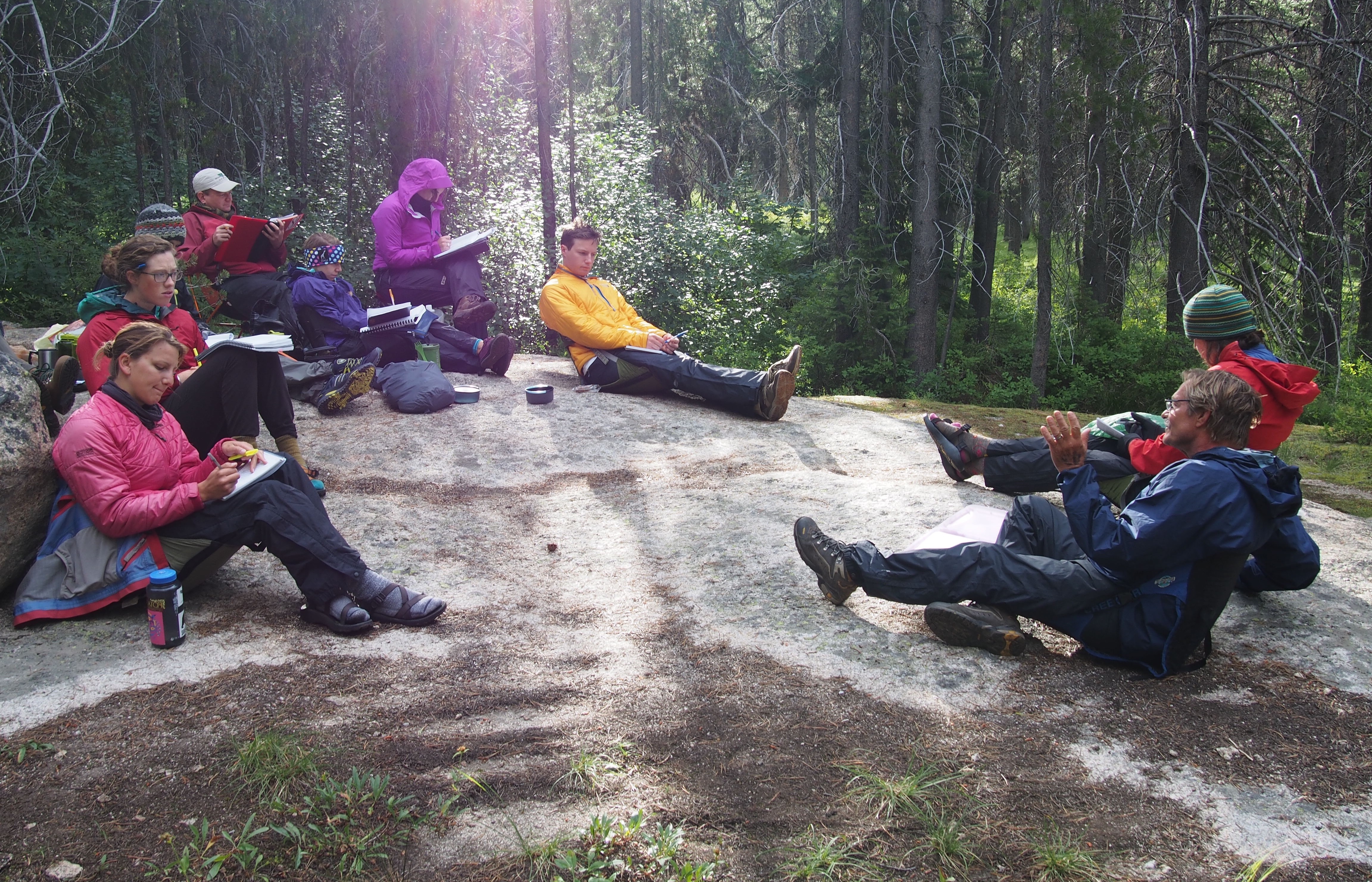 Students sitting in a circle in the forest while Jack Tuholske lectures