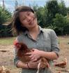 Julia Lee wearing a green shirt, smiling and holding a chicken