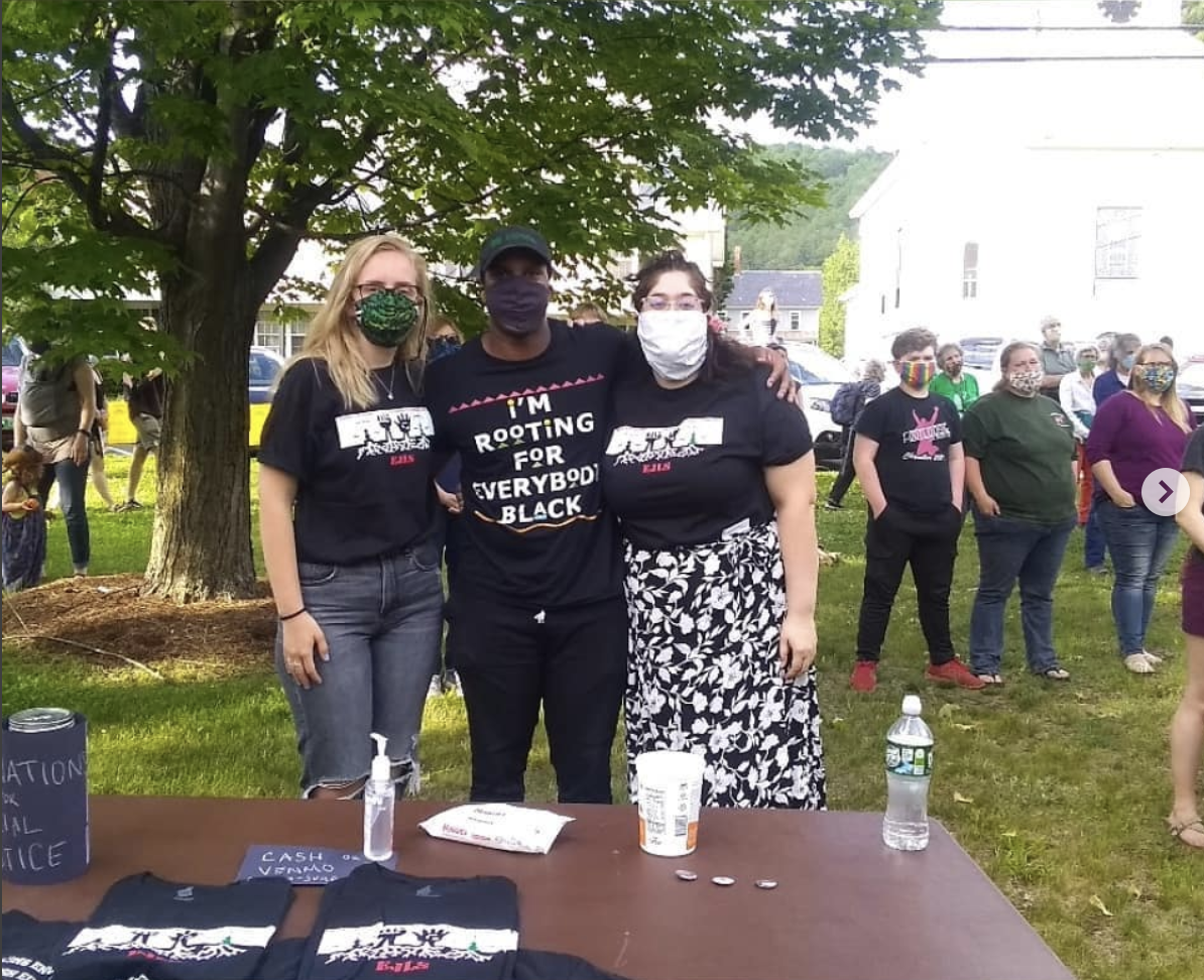 3 EJLS students wearing masks behind a table on the South Royalton green, selling EJLS t-shirts at a Black Lives Matter rally.
