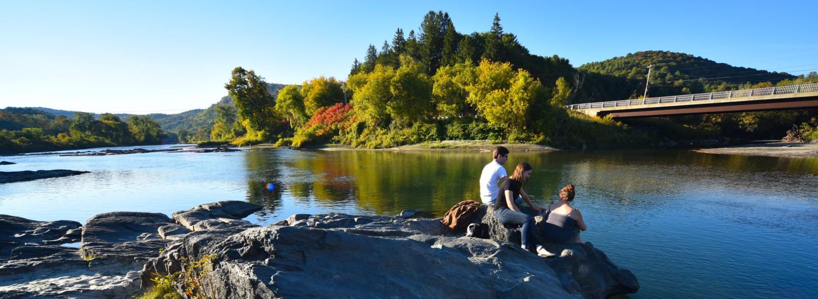 Vermont Law School students sit on a rock on the banks of the White River in South Royalton.