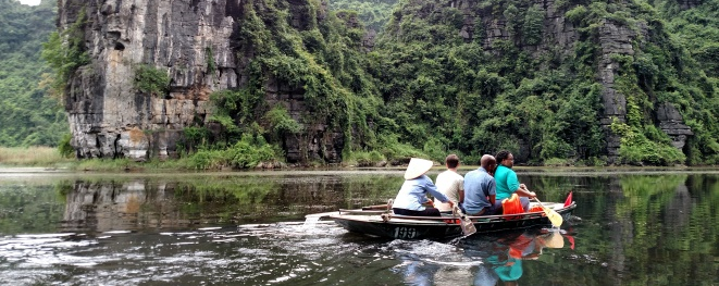 People in a boat next to dramatic cliffs in Southeast Asia