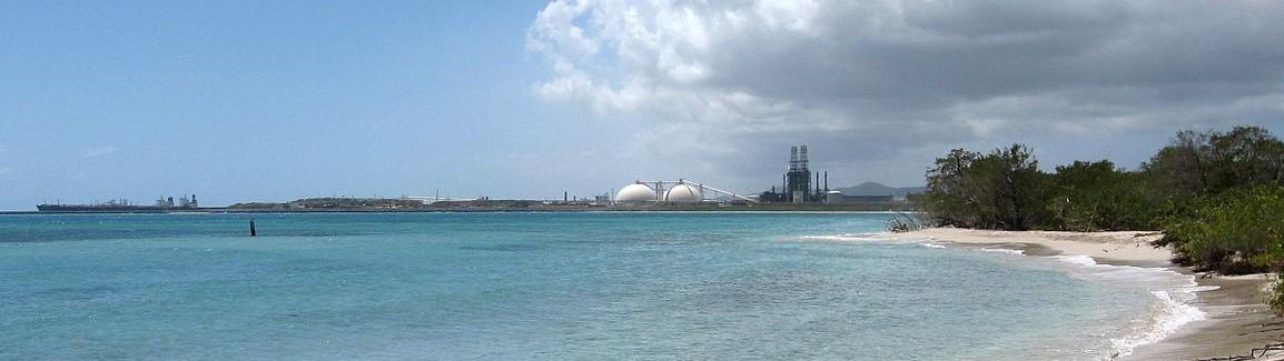 An idyllic beach in St. Croix with an oil refinery in the distance.