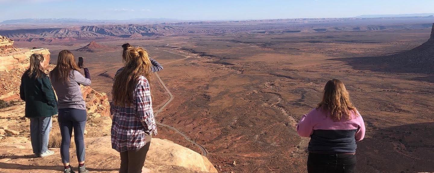 Students standing on the edge of a cliff in the desert of southern Utah