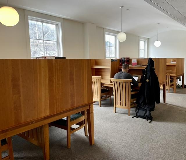 a student studies at a carrel on campus level of the library