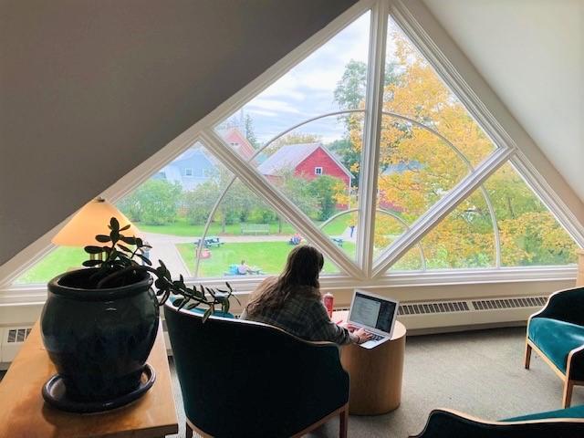 a student studies in the library loft overlooking the green