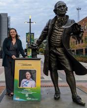 Laura Fox standing with her banner and George Mason Statute