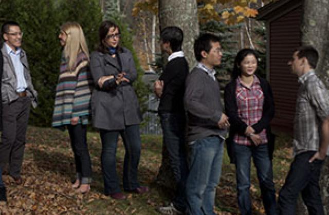 students gather after class on the lawn in front of Debevoise with fall leaves all around