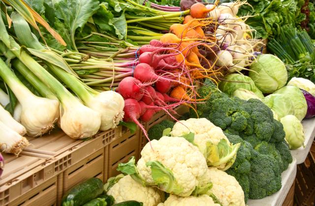 Vegetables at a farmers market stand: onion, beets, turnips, cauliflower, cabbage, and broccoli.
