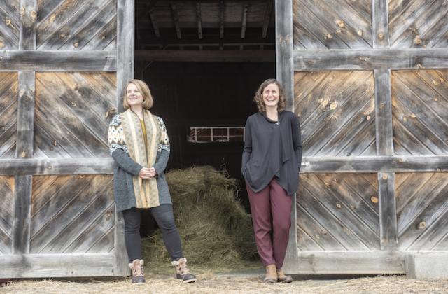Clinical Teaching Fellow Whitney Shields and Clinic Director Sophia Kruszewski stand outside a wooden barn door in South Royalton, Vermont.