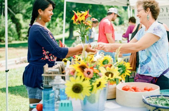 A young woman selling flowers at a farmers' market.