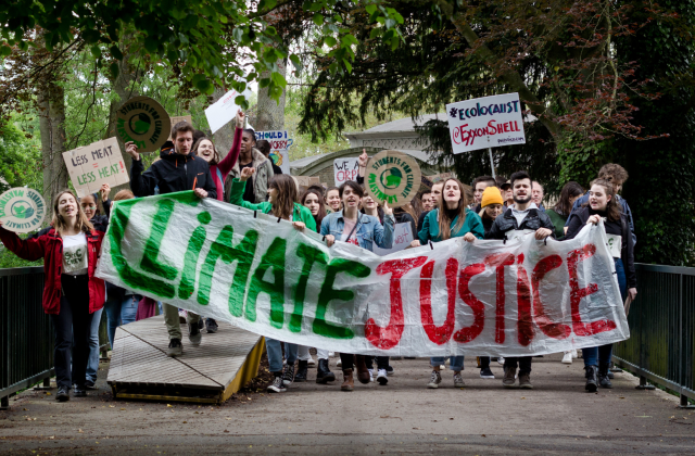 Young people at a protest, holding a banner that says "Climate Justice"