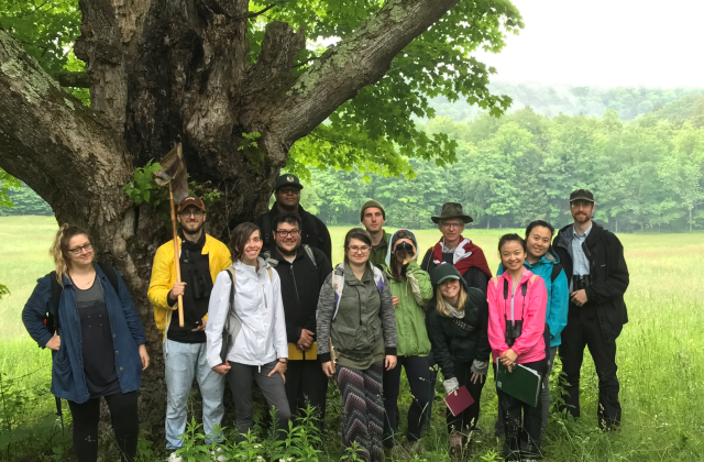 Students in a field ecology course pose for a photo under a tree in a field.