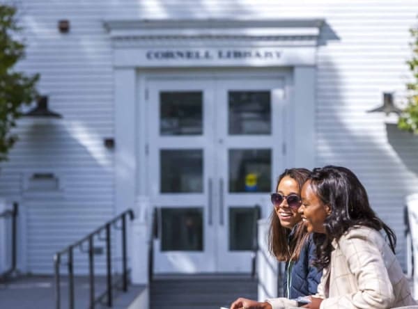 Two student sitting and talking outside of Cornell Library.