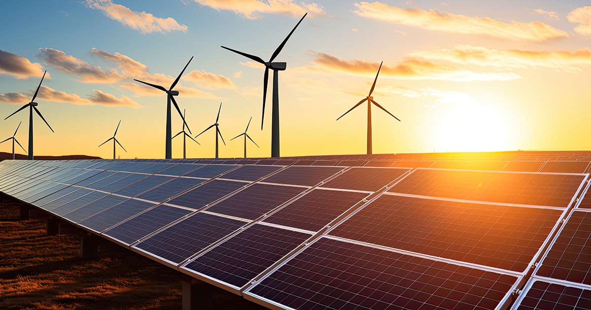 Solar panels and wind turbines at sunset.
