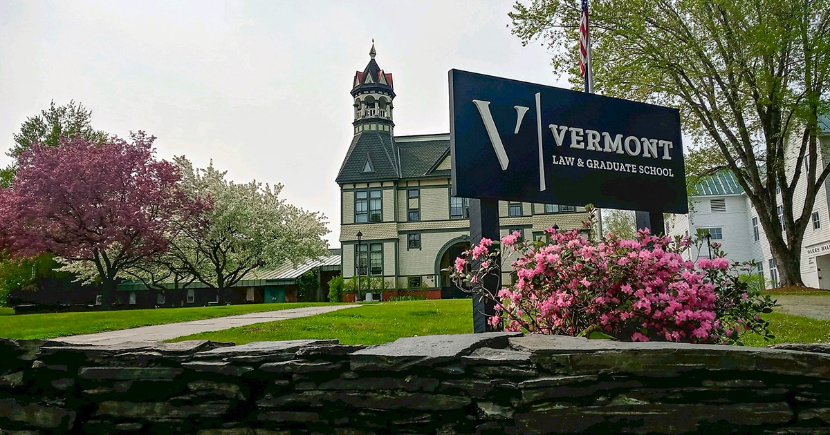 View of Debevoise Hall with Vermont Law and Graduate School sign in spring.