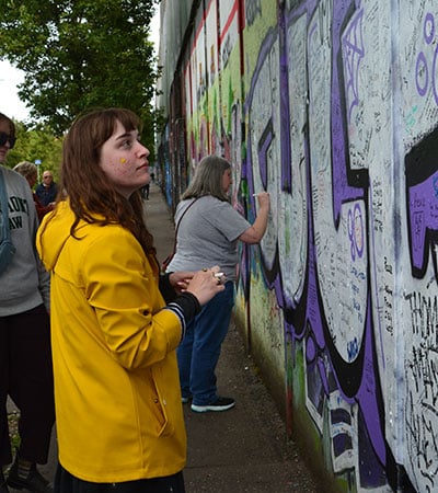 VLGS Restorative Justice students view Belfast’s murals and peace walls, signing as visitors.