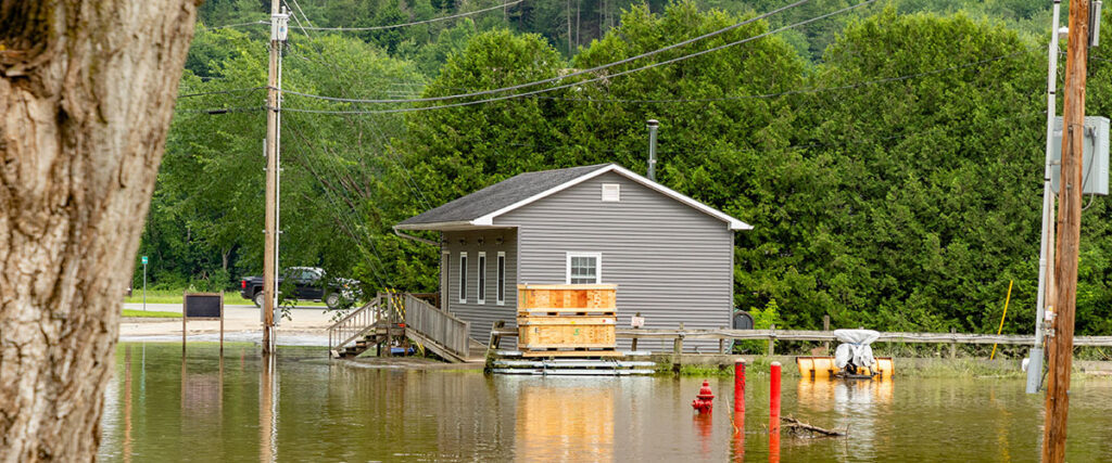 A small grey building surrounded by flooding