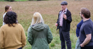 Mark James, interim director of the Institute for Energy and the Environment, speaks to students in a field.