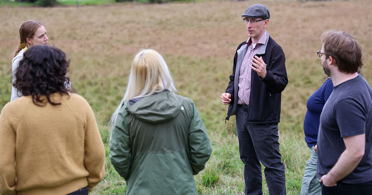 Mark James, interim director of the Institute for Energy and the Environment, speaks to students in a field.