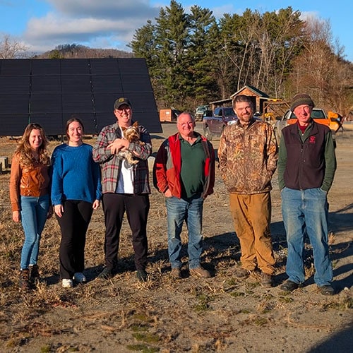 Energy student clinicians stand with Tunbridge locals in front of a 10.7 kW solar array.