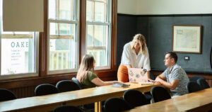 Three students gather around a laptop in a VLGS classroom