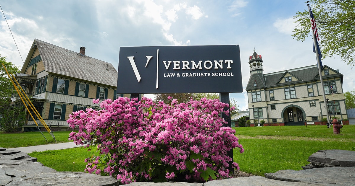 The VLGS sign and pink flowers in front of Debevoise Hall on a sunny, spring day