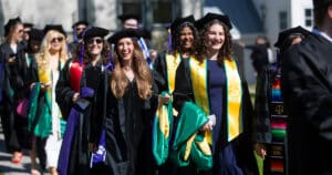 A candid photo of multiple students smiling as they prepare to line up for Commencement 2026 procession